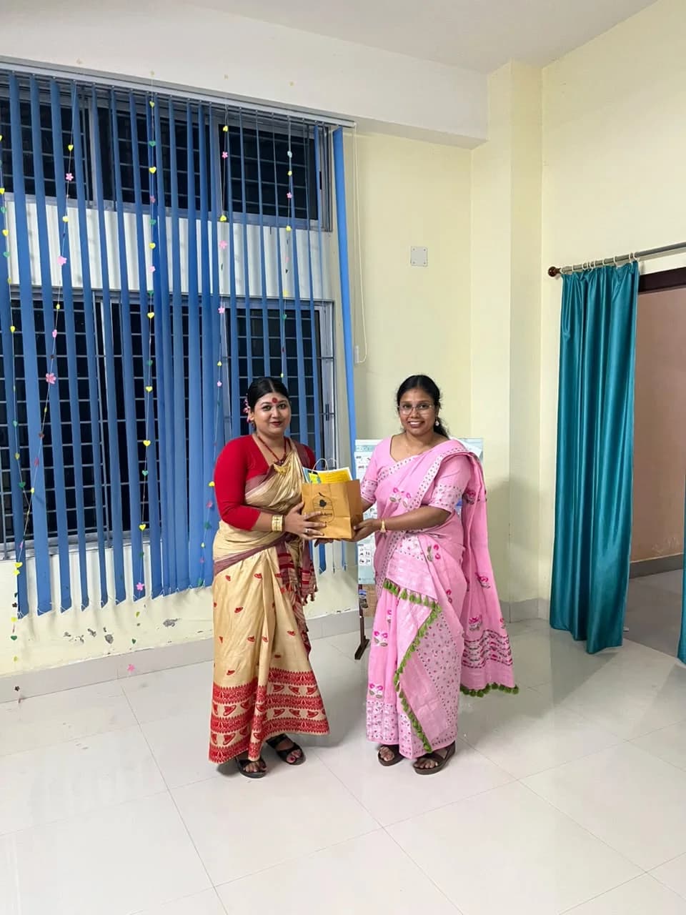 A guest in traditional Assamese attire receiving a Windsong Café gift bag