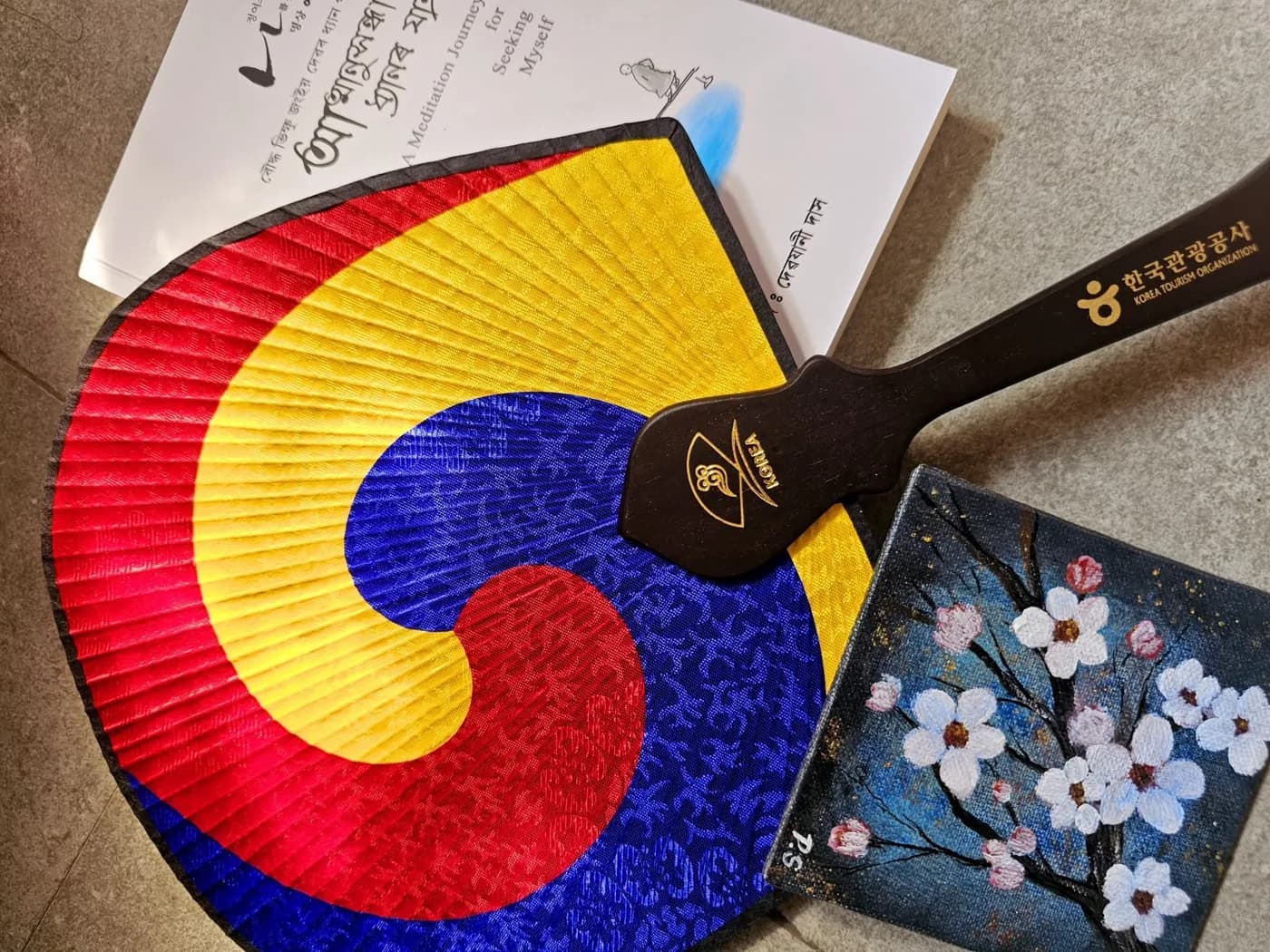 A Korean wooden fan, the book A Meditation Journey for Seeking Myself and a hand-painted cherry blossom canvas